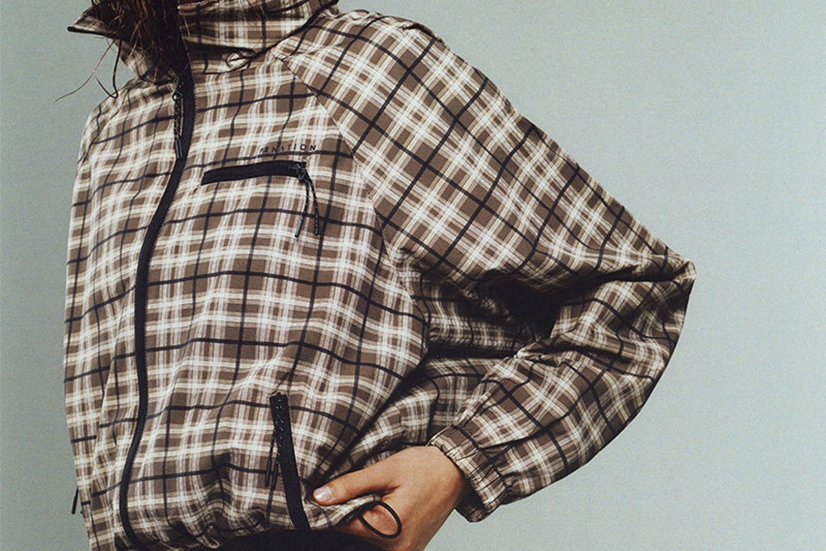 Travel Day Uniform cover: a check trek jacket, brown trousers and boat-neck top from the edit